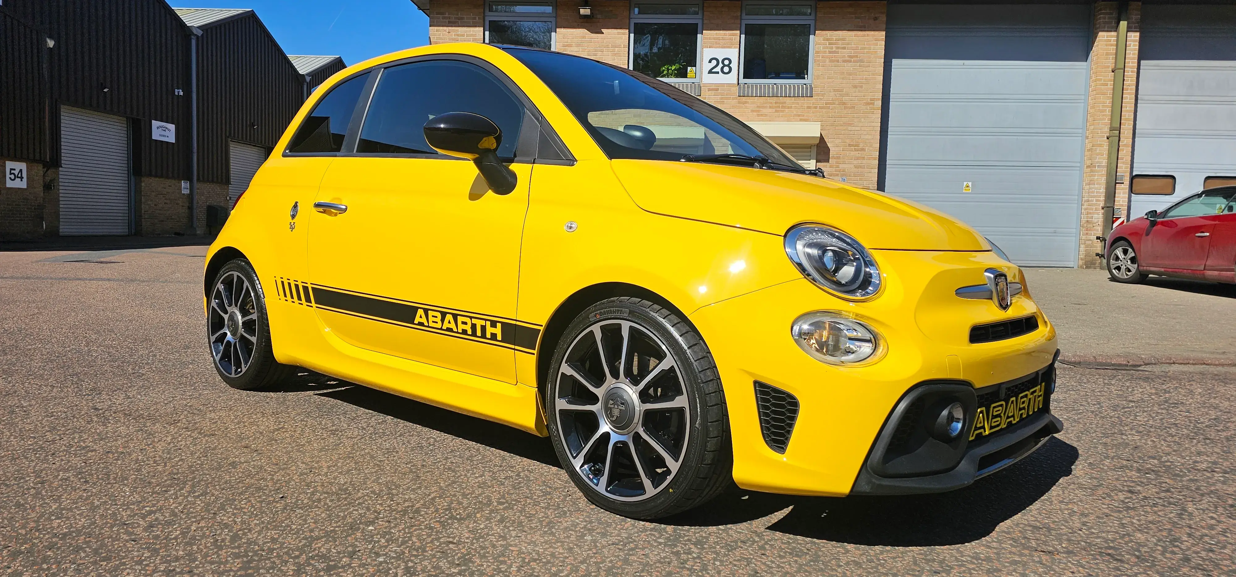 A small yellow car parked in a parking lot.