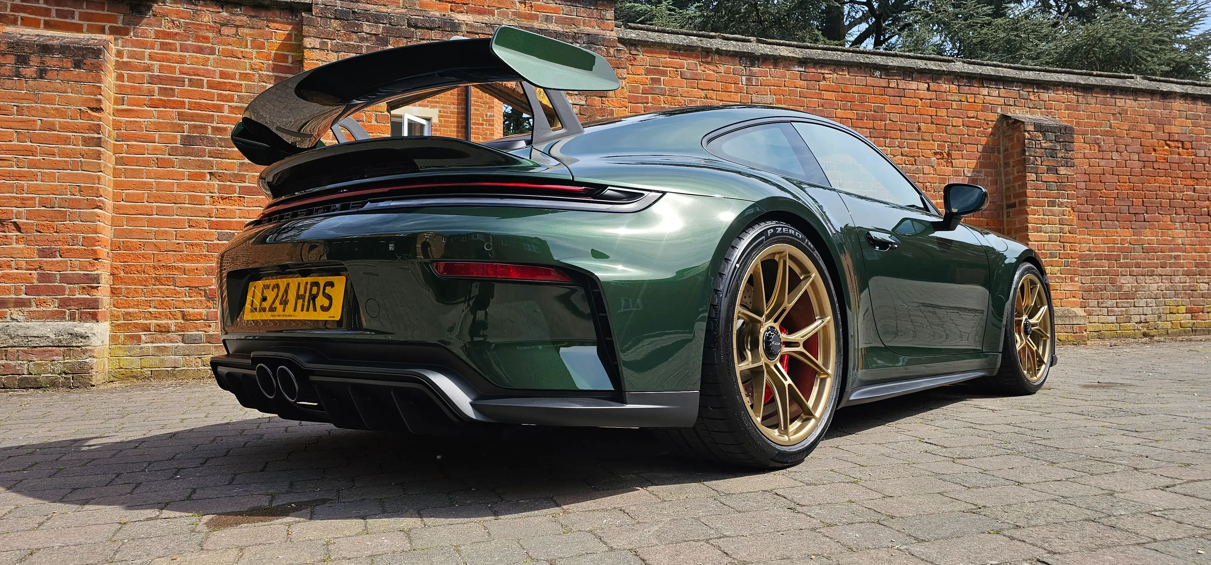 A green sports car parked in front of a brick wall.