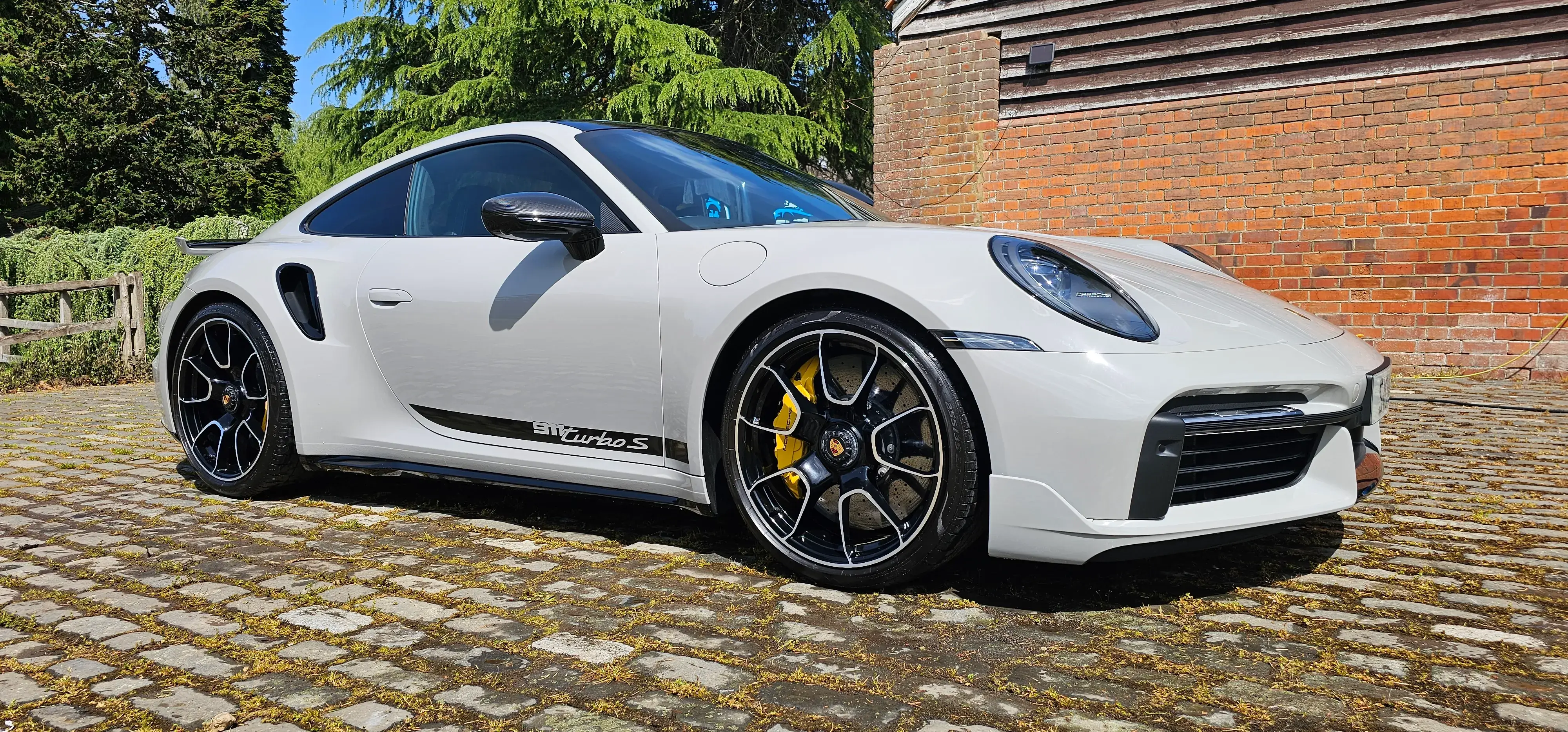 A white sports car parked in front of a brick building.