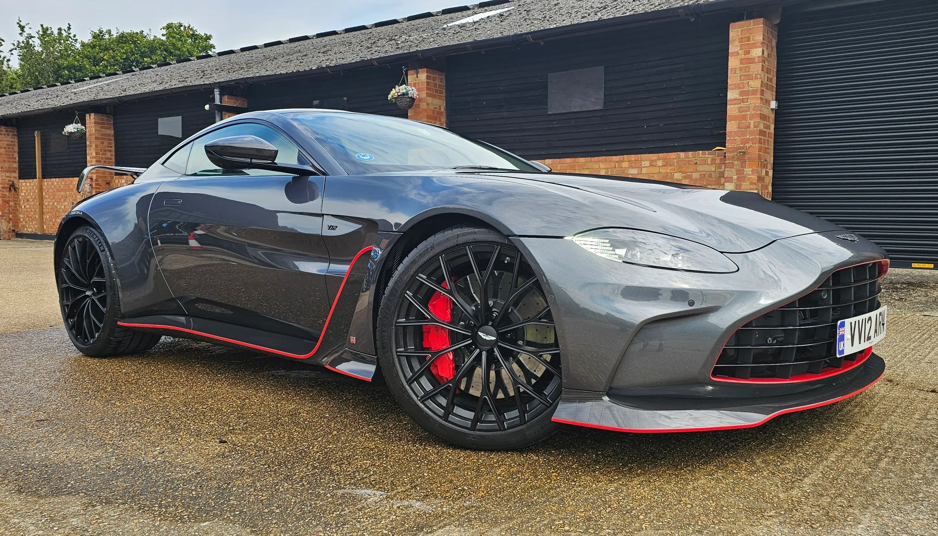 A grey sports car parked in front of a garage.