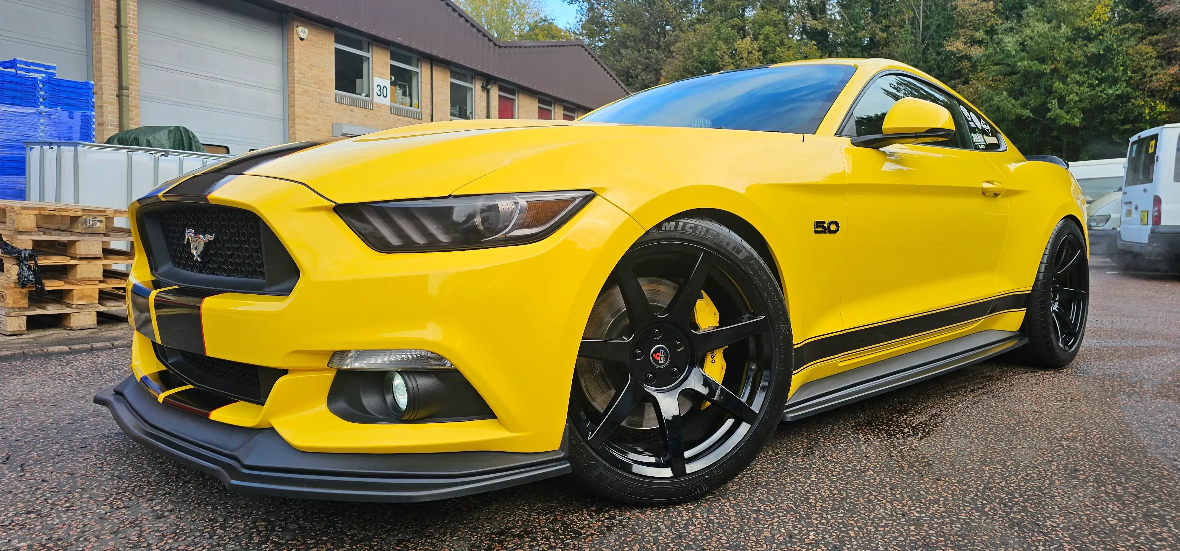 A bright yellow mustang parked in a parking lot.